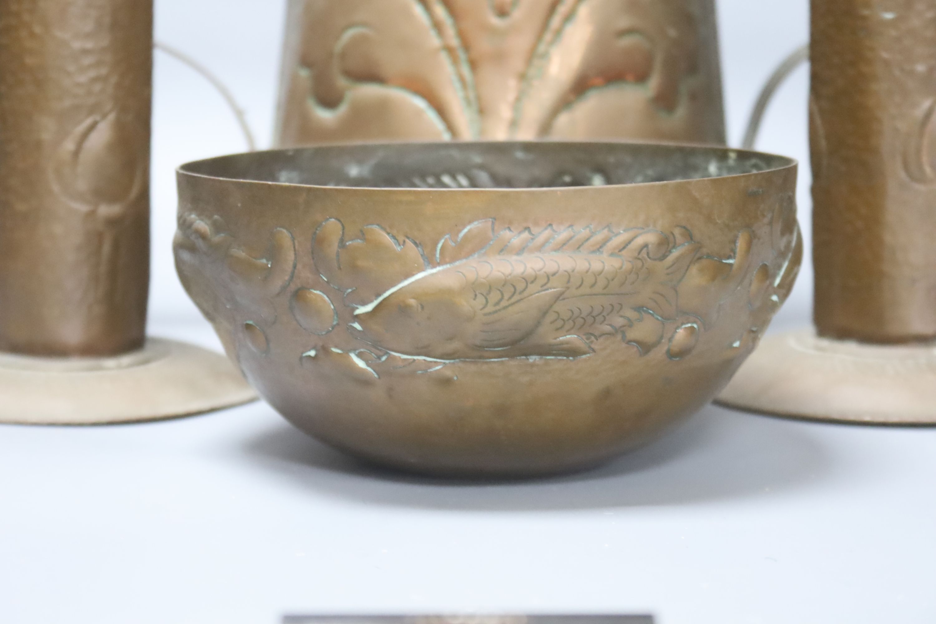 A Newlyn copper 'fish' bowl, together with a pair of Art Nouveau planished copper candlesticks and a similar two handled jug, largest 22cm